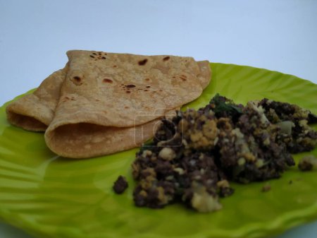 Nahaufnahme von Ziegenblut-Braten mit Eiern Kombination mit Chapathi oder Parota in einem grünen Teller isoliert auf weißem Hintergrund.