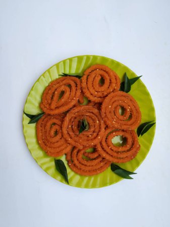 Chakli-Gruppe in einer grünen Platte isoliert auf weißem Hintergrund. Indischer Snack Chakli oder Chakali aus frittierten Teilen eines Linsenmehlteigs