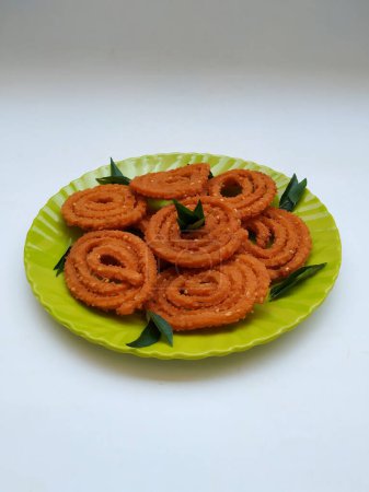 Chakli-Gruppe in einer grünen Platte isoliert auf weißem Hintergrund. Indischer Snack Chakli oder Chakali aus frittierten Teilen eines Linsenmehlteigs