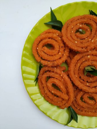 Group of Chakli in a Green Plate isolated on White Background. Indian Snack Chakli or chakali made from deep frying portions of a lentil flour dough