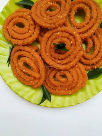 Group of Chakli in a Green Plate isolated on White Background. Indian Snack Chakli or chakali made from deep frying portions of a lentil flour dough