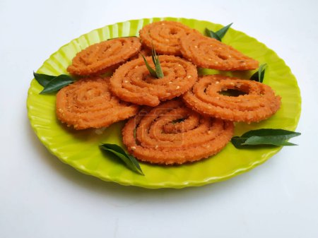 Groupe de Chakli dans une plaque verte isolée sur fond blanc. Snack indien Chakli ou chakali fait à partir de friture portions d'une pâte de farine de lentilles