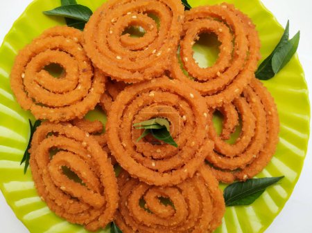 Groupe de Chakli dans une plaque verte isolée sur fond blanc. Snack indien Chakli ou chakali fait à partir de friture portions d'une pâte de farine de lentilles