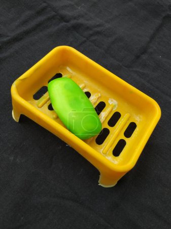 Nahaufnahme von gebrauchter grüner Badeseife in einer orangefarbenen Plastikbox isoliert auf schwarzem Hintergrund