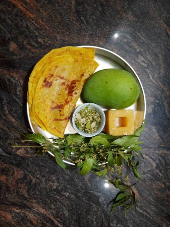 Closeup of beautiful and delicious Ugadi special food like Mango, Jaggery, Neem and Sweet Poli or Obbattu.