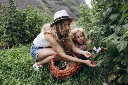Téléchargez les photos : Maman et fille jouent dans le jardin, heureux temps ensemble. Apprendre à connaître la nature, les soins et la santé. Partager du temps avec la famille. Bonheur et éducation, s'entraider - en image libre de droit