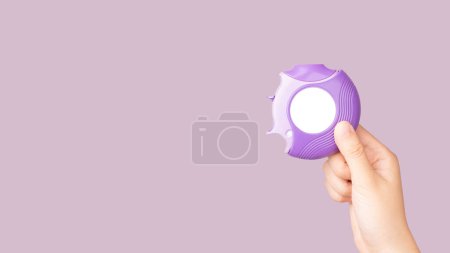 Téléchargez les photos : Asthme et concept de BPCO. Main tenant médicament poudre sèche inhalateur sur fond violet. Produit pharmaceutique est utilisé pour l'inflammation pulmonaire et prévenir les crises d'asthme. - en image libre de droit