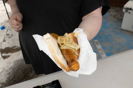 Téléchargez les photos : Une personne méconnaissable remettant une saucisse dans du pain à une saucisse traditionnelle australienne barbecue grésille - en image libre de droit
