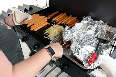 Téléchargez les photos : Une personne méconnaissable cuisinant un barbecue australien traditionnel saucisse grésille, saucisses cuisson sur un barbecue - en image libre de droit