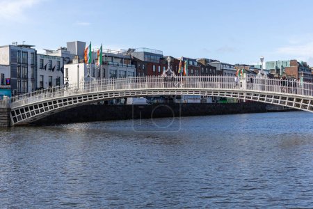 Téléchargez les photos : DUBLIN, IRLANDE - 25 MARS 2023 : Vue journalière de l'emblématique pont piétonnier Penny Hapenny au-dessus de la rivière Liffey au centre-ville de Dublin. - en image libre de droit