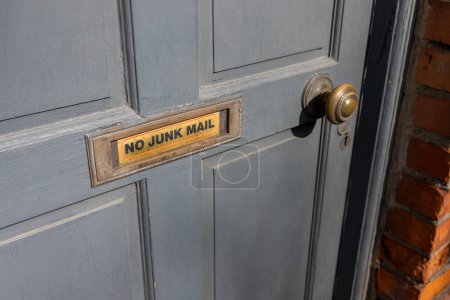  A wooden door with a metal mailbox bearing the inscription no junk mail attached.