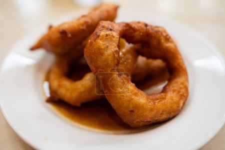 Téléchargez les photos : Picarones de dessert péruviennes traditionnelles avec du miel servi dans une assiette. Une purée de citrouille avec des patates douces frites. Nourriture péruvienne - en image libre de droit