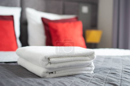 Téléchargez les photos : Accent sélectif sur la pile de serviettes de bain fraîches soigneusement plié sur le lit dans la chambre à coucher à l'appartement moderne - en image libre de droit