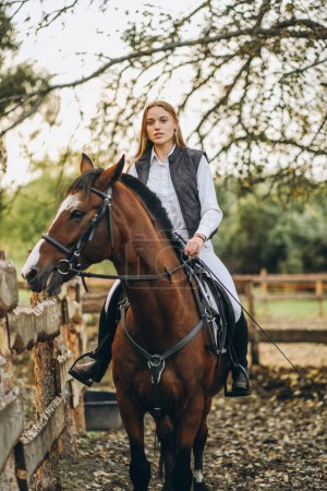 Photo for A young female jockey is sitting on her horse in show jumping training. Preparing for the competition. Love for horses. - Royalty Free Image