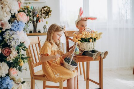 Photo for Two sisters eat sweets on the morning of Easter. Celebrating Easter at home with family. - Royalty Free Image