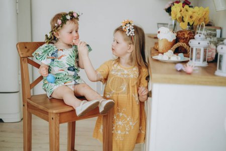 Photo for Two sisters eat sweets on the morning of Easter. Celebrating Easter at home with family. - Royalty Free Image