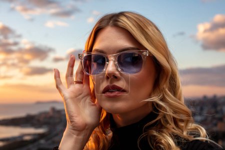 Schöne weibliche Modell trägt bunte Brille bei Sonnenuntergang. Draußen romantisches Porträt einer attraktiven blonden Frau mit Make-up und Brille posiert. Skyline des Istanbuler Archipels (Princess Islands).