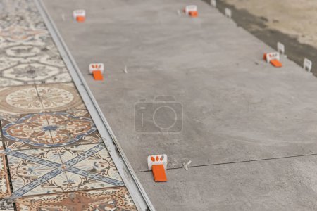Photo for Industrial ceramic builder worker installing floor tile at repair renovation work - Handyman installing ceramic tiles - A special cement mass to fill gaps between the laid ceramics. - Royalty Free Image
