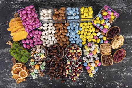 Photo for Heap of sugared almonds and hazelnuts dragees in chocolate isolated on dark background. Handmade colorful chocolate candies filled with nuts. Chocolate candies and Pebblestone chocolate dragees. - Royalty Free Image