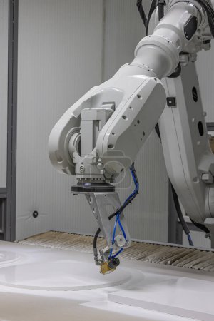  Plan vertical d'un bras robot peignant une chaise en bois dans une usine de meubles. Robot bras peinture spray. Concept de production de haute technologie.