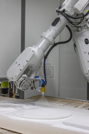  Plan vertical d'un bras robot peignant une chaise en bois dans une usine de meubles. Robot bras peinture spray. Concept de production de haute technologie.