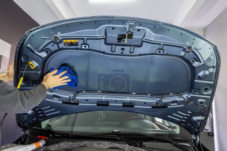 Der Autoservice trägt schalldichtes Bitumenmaterial auf die Motorhaube des Autos auf, passt die Lautstärke des Autos an oder installiert eine Schalldämmung. Schalldämmung im Auto.