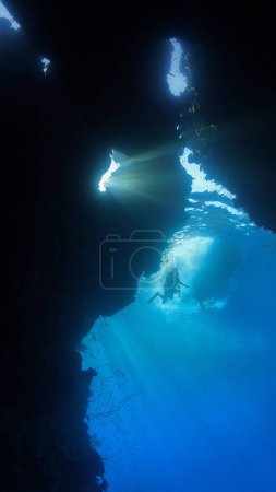 Foto de Foto submarina de rayos de sol en el interior con un buceador en la entrada de una cueva. - Imagen libre de derechos