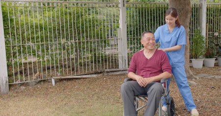 Enfermera asiática que apoya y cuida a un paciente varón adulto al aire libre durante la recuperación de lesiones en las piernas, enfermera que empodera a los pacientes ancianos en su viaje de recuperación