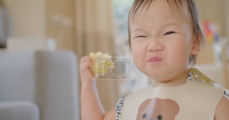 Happy Cute Adorable Little Asian Toddler Girl Disfrutando de comer maíz vegetal fresco Divirtiéndose y sonriendo en casa, Joyful BLW Mealtimes for Healthy Nutrition
