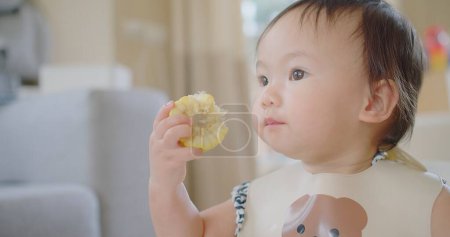 Glücklich Niedlich Liebenswert Kleine Asiatische Kleinkind Mädchen Genießen Essen frisches Gemüse Mais Spaß haben und lächeln zu Hause, Freudig BLW Mahlzeiten für gesunde Ernährung