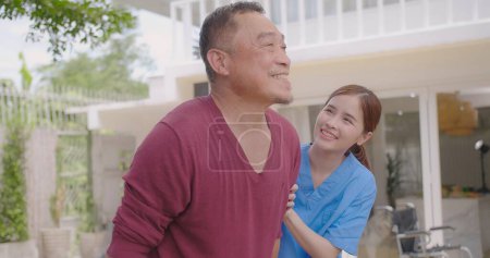 Asiatische Krankenschwester unterstützt und pflegt erwachsene männliche Patienten im Freien während der Genesung von Beinverletzungen, Krankenschwester stärkt ältere Patienten auf ihrer Genesungsreise