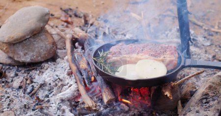 Photo for A pan of meat is cooking over a fire - Royalty Free Image