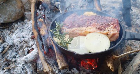 Photo for A pan of meat beef steal is cooking over a fire camping site outdoors - Royalty Free Image