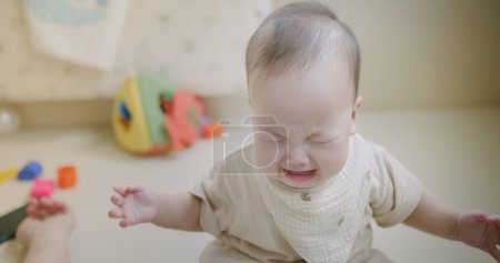Foto de Retrato inocencia infeliz poco asiático bebé bebé niño pequeño niño son llorando triste grito dolor y enojado emoción expresión molesto cara mientras sentado solo en sala de estar en casa - Imagen libre de derechos