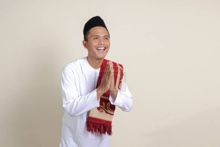 Téléchargez les photos : Portrait d'homme musulman asiatique attrayant en chemise blanche avec crâne montrant des excuses et geste de bienvenue. Image isolée sur fond gris - en image libre de droit