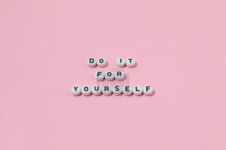 Téléchargez les photos : Vue du dessus de "faites-le pour vous-même" citations faites de perles sur fond rose. concept de motivation et de succès - en image libre de droit