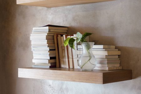 Téléchargez les photos : Empilement de livres sur étagère flottante en bois. Concept d'éducation et de connaissance. Une pile de livres à lire. Maison décoration intérieure - en image libre de droit