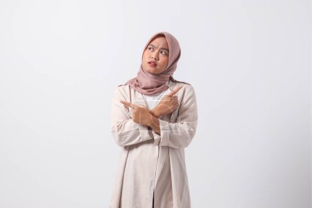 Téléchargez les photos : Portrait de femme hijab asiatique excitée en costume décontracté écartant les mains en faisant un choix, en choisissant entre deux objets. Concept de femme d'affaires. Image isolée sur fond blanc - en image libre de droit