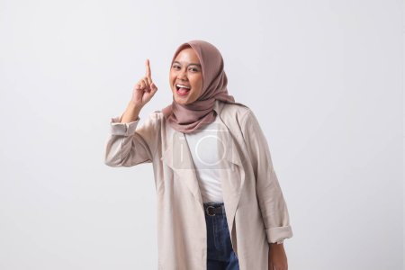 Téléchargez les photos : Portrait de femme asiatique excitée hijab en costume décontracté pointant son index et rappelant quelque chose à faire. Concept de femme d'affaires. Image isolée sur fond blanc - en image libre de droit