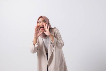 Téléchargez les photos : Portrait de femme hijab asiatique excitée en costume décontracté criant annonce et chuchotant commérages. Concept de femme d'affaires. Image isolée sur fond blanc - en image libre de droit