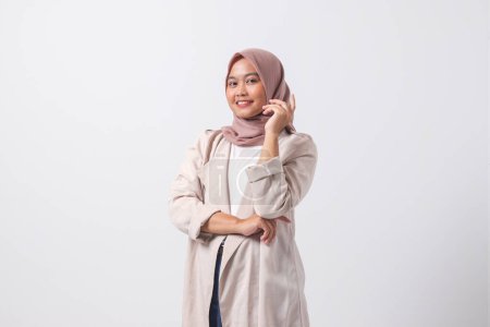 Téléchargez les photos : Portrait de femme hijab asiatique attrayante en costume décontracté se sentant confiant, posant avec geste professionnel de la main. Isolé sur fond blanc - en image libre de droit