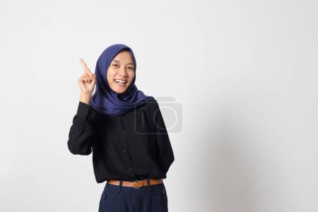 Téléchargez les photos : Portrait de femme hijab asiatique excitée en costume décontracté montrant et pointant vers le haut avec les doigts numéro un tout en souriant confiant et heureux. Concept de femme d'affaires. Image isolée sur fond blanc - en image libre de droit