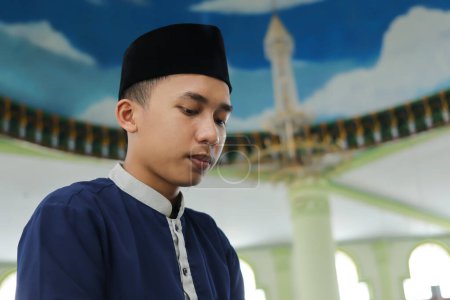 Porträt eines religiösen asiatischen Mannes im muslimischen Hemd, der in der Moschee betet und Salat oder Sholat macht