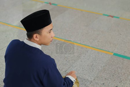 Porträt eines religiösen asiatischen Mannes im muslimischen Hemd, der in der Moschee betet und Salat oder Sholat macht
