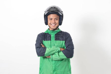 Téléchargez les photos : Portrait de chauffeur de taxi asiatique en ligne portant une veste verte et un casque, debout avec les bras croisés. Image isolée sur fond blanc - en image libre de droit