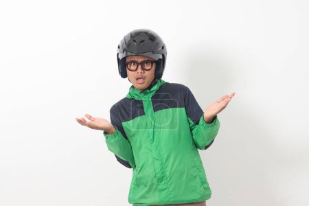 Téléchargez les photos : Portrait d'un chauffeur de taxi en ligne asiatique fatigué portant une veste verte et un casque faisant une drôle de pose. Image isolée sur fond blanc - en image libre de droit