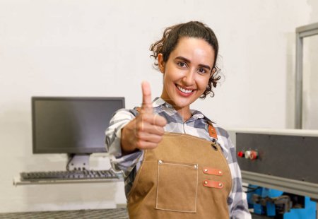 Photo for Portrait Young Latin woman carpenter looking at camera smiling good hands, happy professionals in the machine room furniture carpenter Concept of young people start up and SME small business - Royalty Free Image