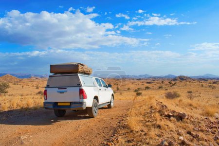 Téléchargez les photos : Voiture hors route avec tente de toit au milieu du paysage namibien. Namibie road trip. - en image libre de droit
