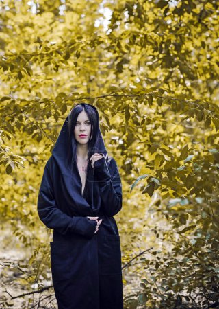 Photo for Woman with dark long hair in black, gothic style, black robe. Mysterious portrait in forest - Royalty Free Image