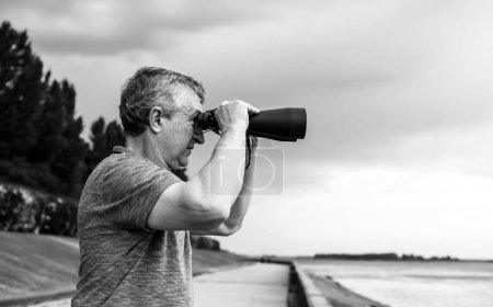  European Mature man looking in a binoculars . Hobby and recreation concept